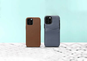 image of 2 iphone cases upright (rear view of the cases) on a marble countertop and teal background